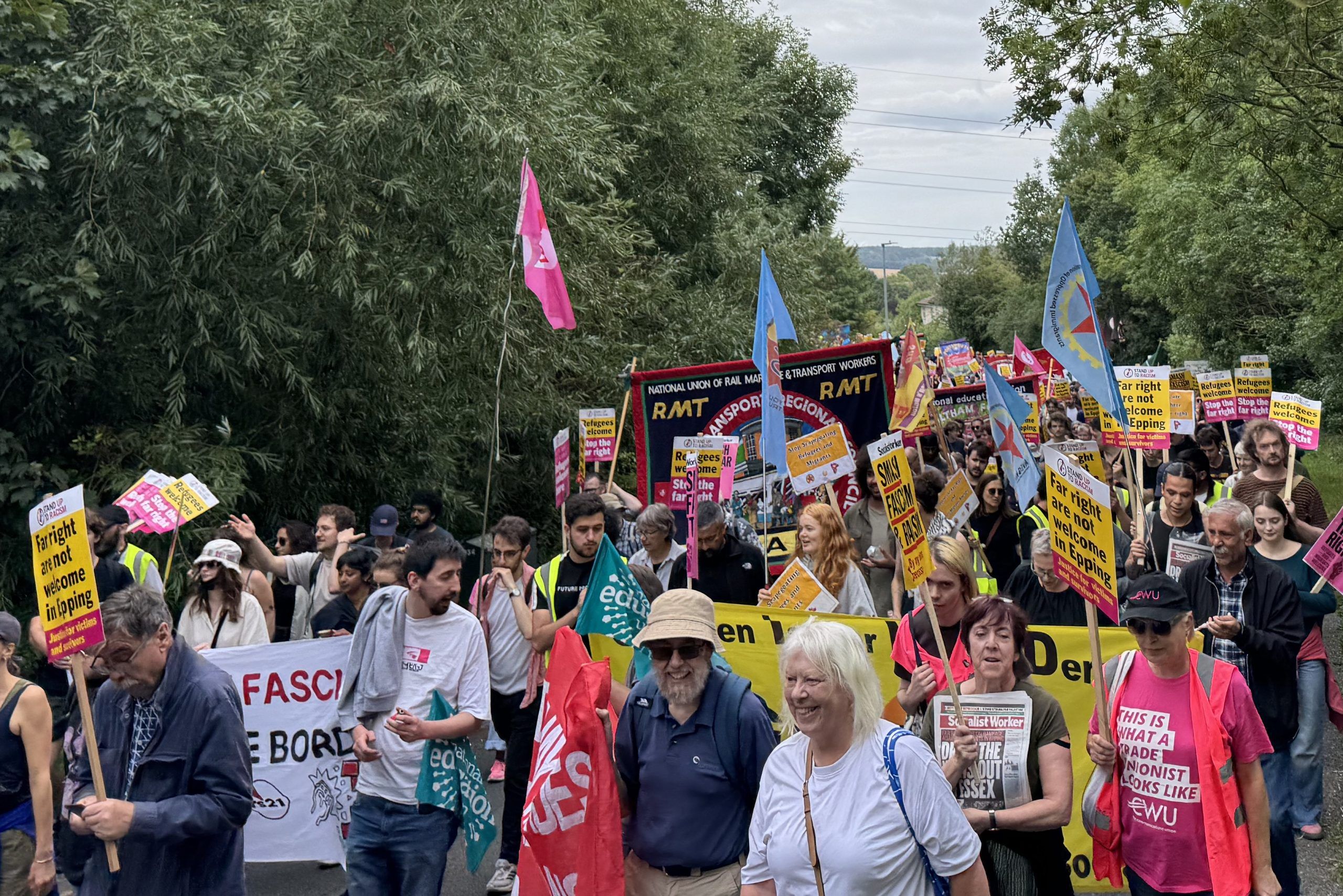 Hundreds of marchers walking through Epping Forest with banners.