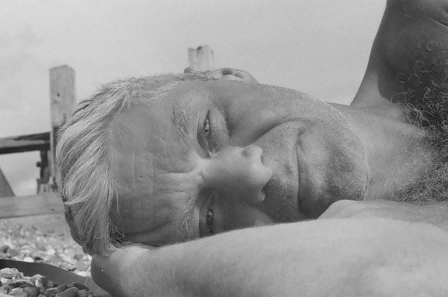 Tom Fogg, in B&W lying on the beach in a photo taken by his son.