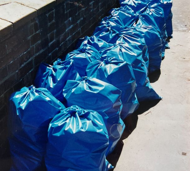 A line of blue refuse bags filled with empty bottles line up outside a student flat. Photo: Elio España